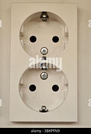A white electrical outlet featuring two sockets is mounted on a wall. The installation appears clean with visible screws, suitable for powering variou Stock Photo