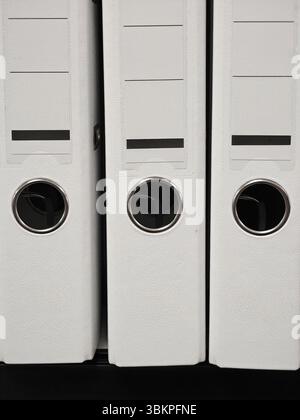 Several white binders arranged neatly on a shelf showcase an organized system for managing important documents in an office environment. The interior Stock Photo
