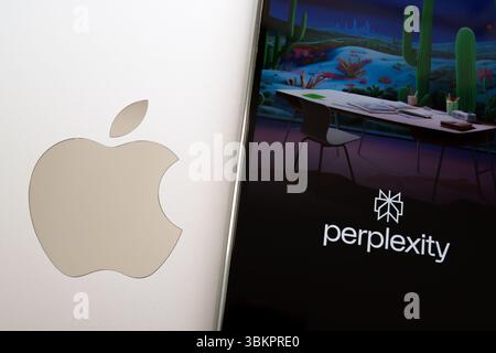 Perplexity loading screen displayed on smartphone next to Apple logo on laptop, representing modern assistant tools across ecosystems. Stafford, Unite Stock Photo
