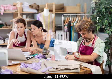 Female dressmaker and client review sketches on laptop Stock Photo