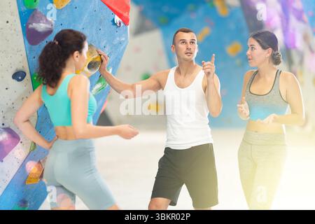Athletic man and two sporty women discussing climbing options near climbing wall Stock Photo