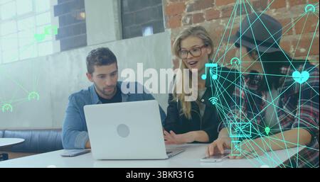 Collaborating professionals reviewing project at co-working space with silver laptop and smartphone Stock Photo