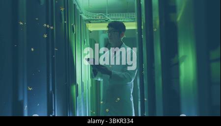 Korean technician in white lab coat inspecting server racks in data center, with tablet computer Stock Photo