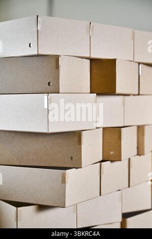 Cardboard box blanks stacked for efficient packaging production in a busy cardboard manufacturing facility Stock Photo