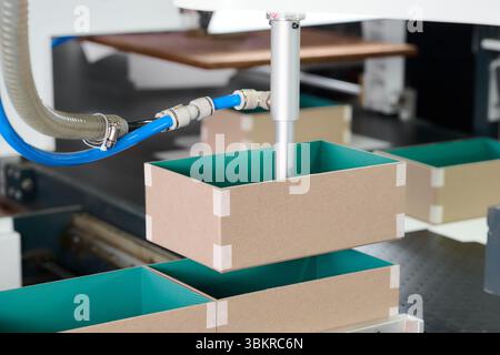 Gluing process in innovative box manufacturing plant with robotic precision and efficiency at work in an automated production environment Stock Photo