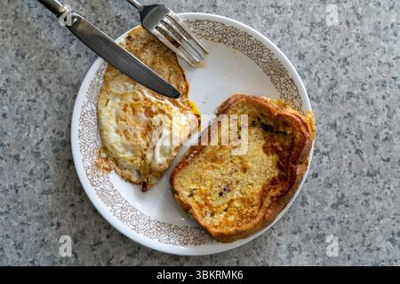 Simple homemade breakfast with golden French toast and pan-fried egg on a vintage plate over a gray countertop—perfect for commercial use, recipe blog Stock Photo