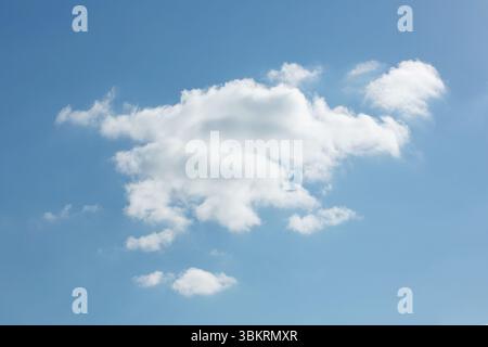 Single cumulus cloud is floating in flat design blue sky, with surrounding wispy clouds Stock Photo