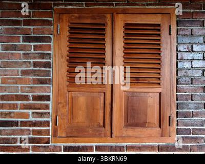 Closed wooden shutters blend with exposed brick walls Stock Photo