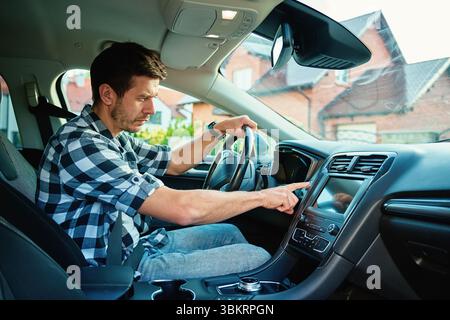 Man sitting in car and pressing engine start button. Starting vehicle using modern ignition technology. Person ready to driving car Stock Photo