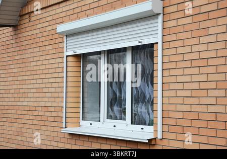 Rolling shutters brick house windows protection. Brick house with metal roller shutters on the windows Stock Photo