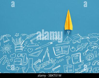 Yellow paper plane flying over hand drawn school items on a blue background, representing back to school, education and learning Stock Photo