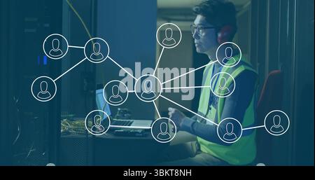 Korean technician in vest and headphones configuring network on laptop in server room, copy space Stock Photo