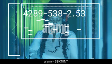 Woman wearing white shirt, headphones monitoring server racks with interface overlay at data center Stock Photo