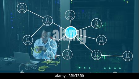 Technician wearing shirt connecting yellow Ethernet cables in server room, with laptop, copy space Stock Photo