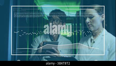 Lab-coated engineers reviewing tablet, clipboard in data center, green-lit racks and data overlay Stock Photo