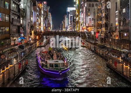 Tourist boats on Dotonbori canal on a wet night. Dotonbori is a principal tourist destination in the Namba district of Osaka, Japan. Stock Photo