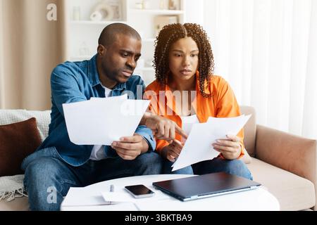 Upset Young Black Couple Suffering Financial Crisis Checking Papers At Home Stock Photo