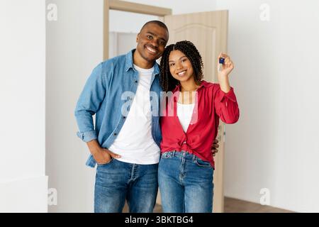 Happy African American couple celebrating home ownership, woman holding house keys Stock Photo