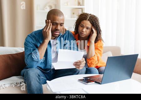 Young African American couple looking distressed as they read financial letter at home Stock Photo