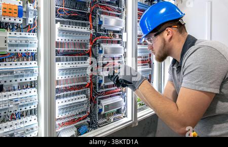 Electrician working in switchboard. Electrical component setup. Cable connection. Stock Photo