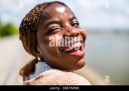 Close up head shot portrait of cheerful young black woman with dental braces. Stock Photo