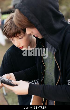 Two boys closely observing something during outdoor camping trip Stock Photo