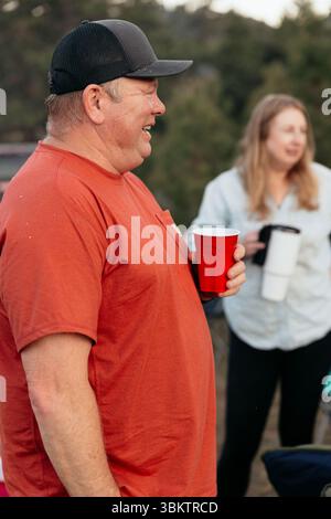 Man wearing baseball cap holding red plastic cup and smiling Stock Photo