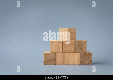 Wooden square blocks arranged in pyramid shape. Isolated on light background, copy space. Stock Photo