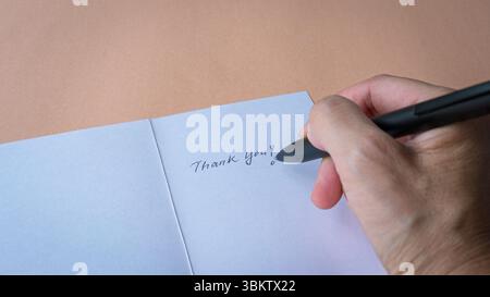 Woman writing on a thank you card, close up view. Stock Photo