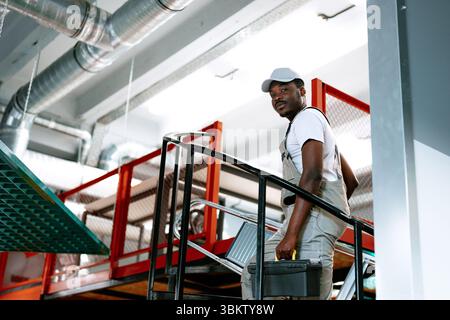 Skilled worker installing ventilation pipes in modern facility during daylight hours Stock Photo