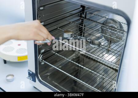 Scientist places samples in laboratory oven for analysis, quality control, and research in science and industry labs. Stock Photo