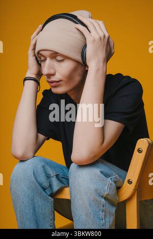 A young person wearing headphones, sitting with closed eyes, deeply immersed in music Stock Photo