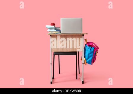 Modern school desk with backpack, laptop and stationery on pink background Stock Photo