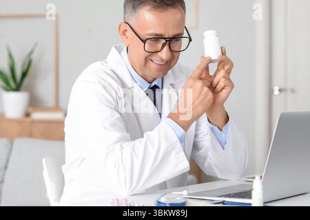 Mature doctor showing pills to patient online at home Stock Photo