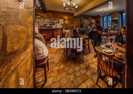The rustic dining room at the Auberge-Restaurant Cul de Paille in Poitiers has existed in this form since 1843. One of the special features of the Auberge Le Cul de Paille is that guests can choose their own table wine in the cellar and that many famous artists, such as Jaques Brel, have immortalised themselves on the walls with autographs, sayings and drawings. Rue Théophraste Renaudot, Poitiers, Nouvelle-Aquitaine, France Stock Photo