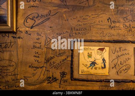 The rustic dining room at the Auberge-Restaurant Chez Cul de Paille in Poitiers has existed in its current form since 1843. Its walls are covered with numerous signatures of famous personalities, including French artists, singers and actors such as Arletty, Georges Brassens, Claude François, Jean Marais, Charles Aznavour, Yves Montand, Jaques Brel and Coluche. One of the special features of the Auberge Le Cul de Paille is that guests can choose their own table wine in the cellar and that many famous artists, such as Jaques Brel, have immortalised themselves on the walls with autographs, saying Stock Photo