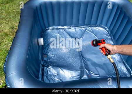 Bavaria, Germany - June 23, 2025: A man fills an inflatable whirlpool in the garden with water, perfect for cooling off on warm summer days and relaxing hours in your own outdoor area *** Ein Mann befüllt einen aufblasbaren Whirlpool im Garten mit Wasser, perfekte Abkühlung an warmen Sommertagen und entspannte Stunden im eigenen Outdoor Bereich Stock Photo