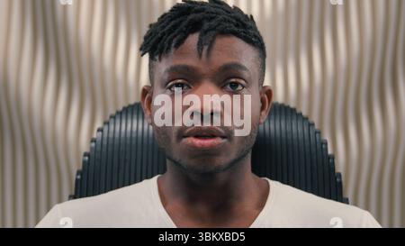 Close up portrait African American ethnic man male guy serious mood unsmiling confident emotion headset in futuristic studio futurism room looking at Stock Photo