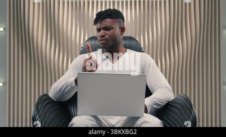 African American man gamer programmer student businessman business male guy laptop using internet online gaming modern futuristic room showing no not Stock Photo