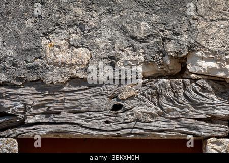 Close up of an old oak lintel beam supporting a stone and plaster wall above Stock Photo