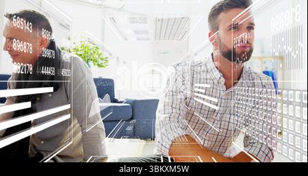 Sitting bearded man in checked shirt reviewing chart overlays at office lounge, with potted plant Stock Photo