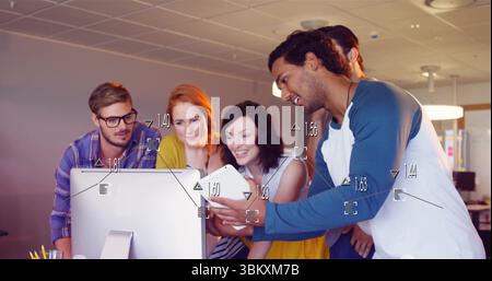 Collaborating five coworkers leaning around monitor at office, with smartphone and pen holder Stock Photo
