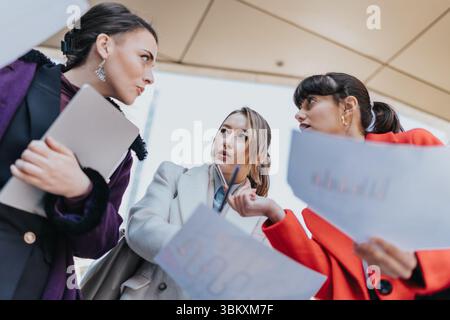 Three professional businesswomen collaborating on a project outdoors, analyzing data and charts Stock Photo