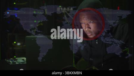Man wearing hoodie hacking laptop in data center with server racks and map overlay, copy space Stock Photo