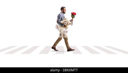 Man with a bunch of red roses and a teddy bear at a zebra crossing isolated on white background Stock Photo
