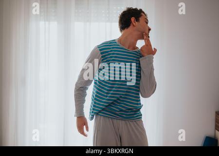 Young man in comfortable attire expressing emotions in a bright room Stock Photo