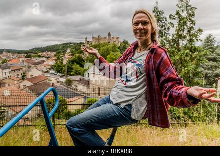 A woman on a Vélorail handcar poses against the backdrop of the medieval upper town of Chauvigny (Nouvelle-Aquitaine, France), with the castle ruins and the collegiate church of Saint-Pierre on the rocky outcrop. Chauvigny is home to five medieval castles built by various feudal lords within a very small area, making it one of the most historically remarkable towns in the Vienne region. Velorail is a type of bicycle railway that can be used for tours in various places in France. Allée de la Grondine, Chauvigny, Nouvelle-Aquitaine, France Stock Photo