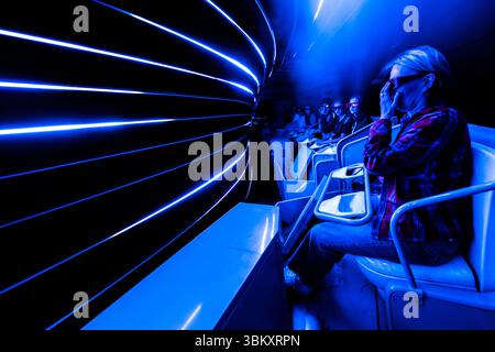 Visitors wearing 3D glasses in a moving ride at Futuroscope theme park. Blue, glowing concentric arcs of light are created by the ride’s high speed. The Futuroscope near Poitiers is an amusement park that specialises in futuristic themes, multimedia experiences and innovative attractions. Avenue René Monory, Chasseneuil-du-Poitou, Nouvelle-Aquitaine, France Stock Photo