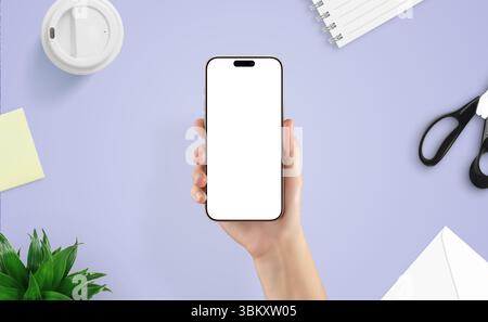 Top view of female hand holding smartphone over creative desk. Ideal mockup for showcasing mobile apps, interface design, or digital tools Stock Photo