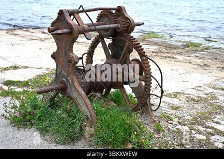 Old rusty cable roller - aka hand winch or boat winch on harbourside, with samphire growing around it, La Seyne-sur-Mer, France April Stock Photo
